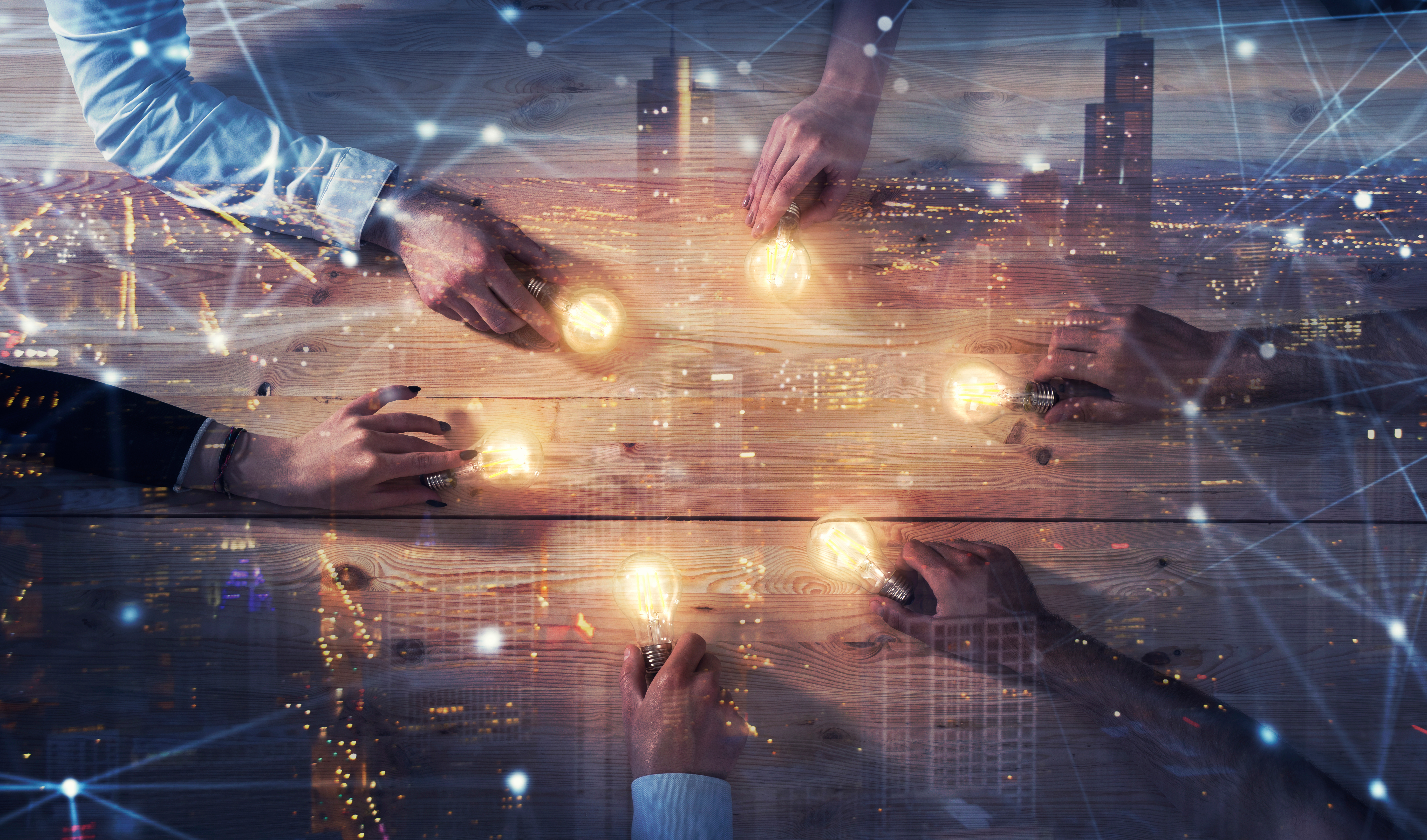 hands holding light bulbs with a city scape image in background